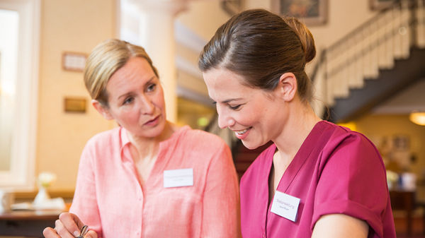 Zwei Pflegerinnen unterhalten sich miteinander.