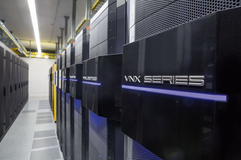 Blick in einen Hochsicherheitsbereich des DATEV-Rechenzentrums mit mehreren Reihen schwarzer Serverracks der VNX Series. Die Hardware ist mit blauen LED-Linien beleuchtet, Kabelsysteme verlaufen an der Decke. Der Raum ist klar strukturiert, mit technischem Bodenbelag und regulierter Beleuchtung – Symbol für Digitalisierung und IT-Sicherheit.