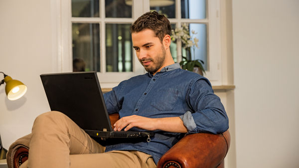 Ein junger Mann arbeitet am Laptop.