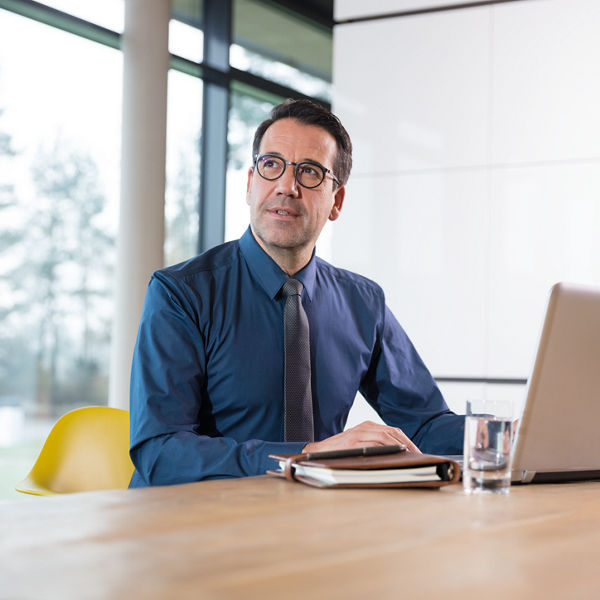 Mann im Büro sitzend mit Laptop