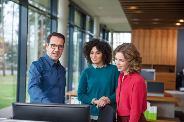 Drei Kanzleimitarbeitende unterhalten sich und blicken in einen Laptop.
