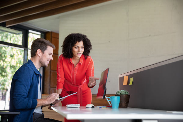 Zwei Mitarbeitende einer Kanzlei unterhalten sich an einem Schreibtisch.
