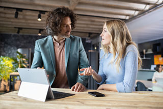 Frau erklärt Mann etwas anhand des Tablets.