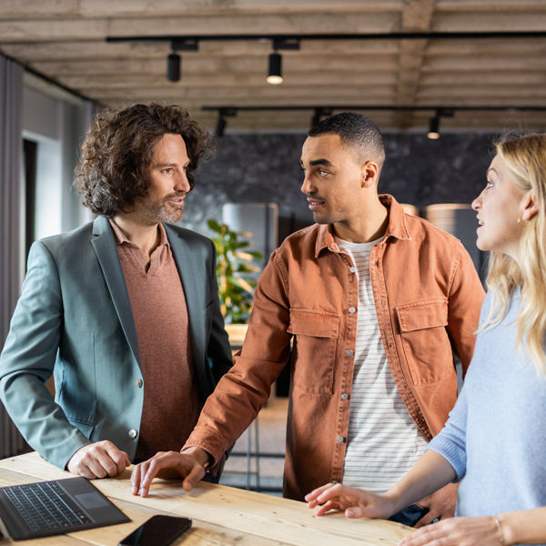 Drei Personen vor einem Laptop