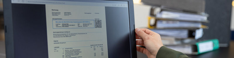 Hand am Bildschirm mit Rechnung