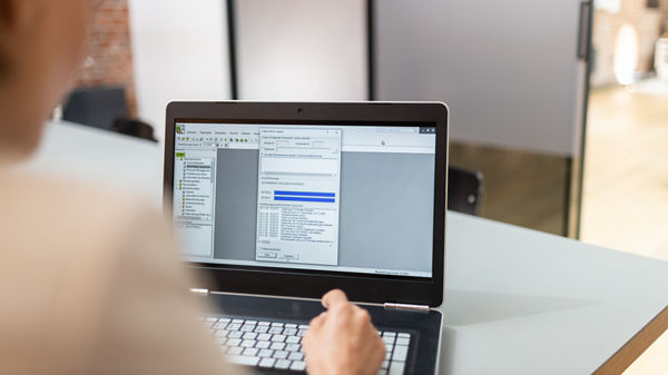 Hand tippt auf Laptop.