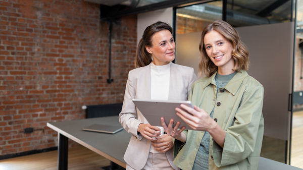 Steuerberaterin und Mandantin unterhalten sich und blicken auf Tablet.