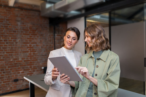 Steuerberaterin und Mandantin blicken gemeinsam auf ein Tablet.
