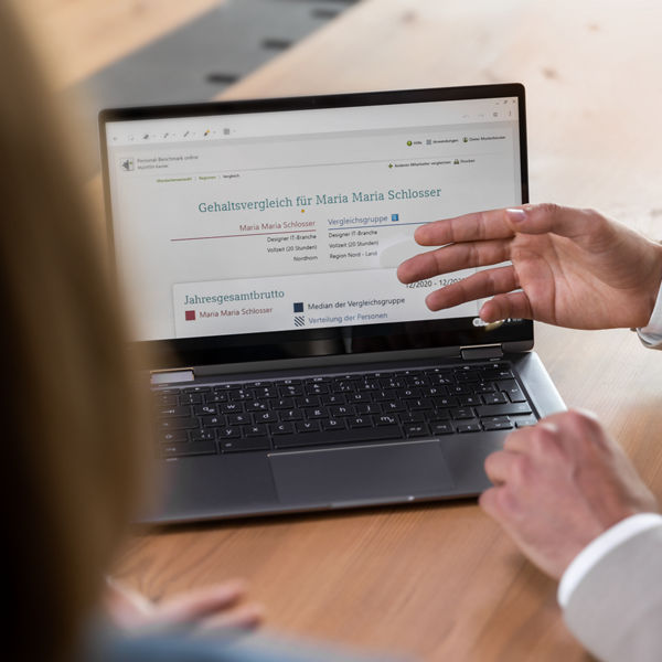 Steuerberater zeigt seiner Mandantin eine Auswertung am Laptop.