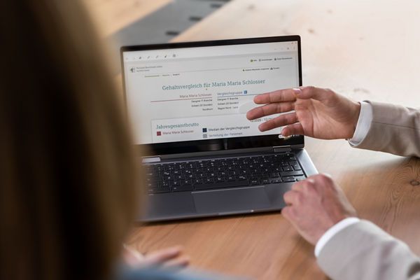 Steuerberater zeigt Mandantin eine Auswertung auf dem Laptop.