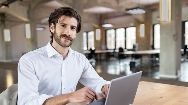 Steuerberater sitzt an Schreibtisch und arbeitet am Laptop.