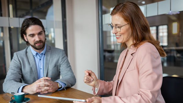 Mann und Frau vor einem Tablet-PC stehend im Büro