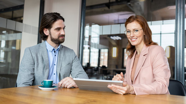 Mann und Frau vor dem Laptop sitzend im Büro