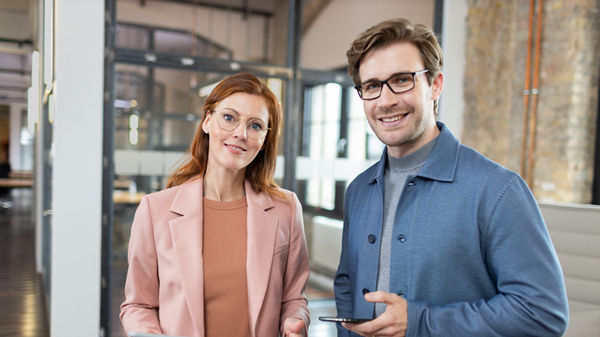 Mann und Frau vor dem Laptop stehend im Büro