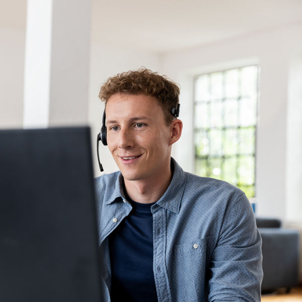 Ein Mann sitz im Büro mit dem Laptop und telefoniert