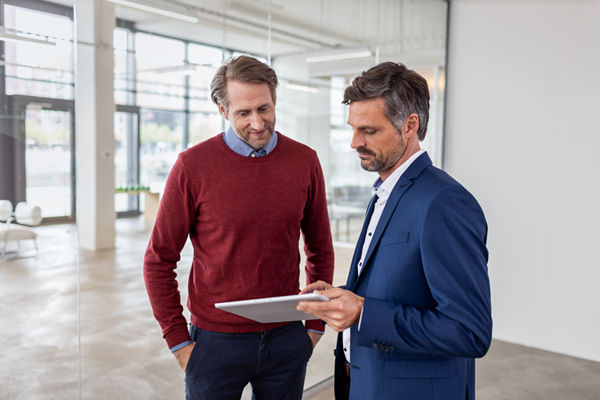 Steuerberater zeigt seinem Mandanten etwas auf einem Tablet.
