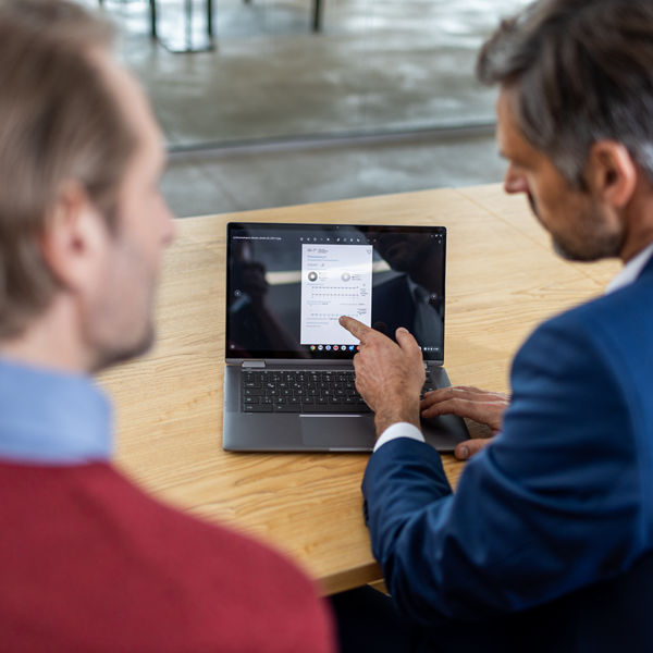 Steuerberater zeigt Mandant etwas auf seinem Laptop.