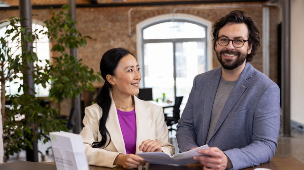 Zwei Männer und eine Frau sitzen im Büro vor dem Laptop