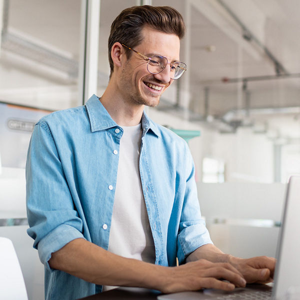 Mann sitzt vor einem Laptop.