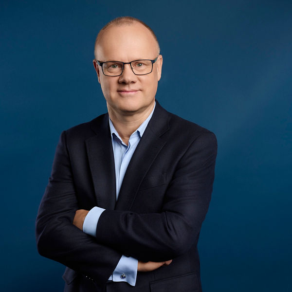 Robert Mayr, CEO der DATEV eG, mit dunklem Sakko und hellblauem Hemd vor blauem Hintergrund.