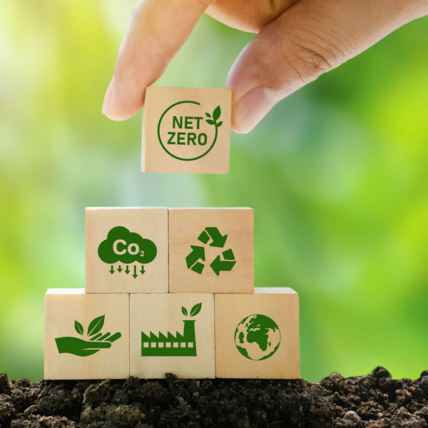 Hand stapelt Würfel mit Nachhaltigkeits-Symbolen