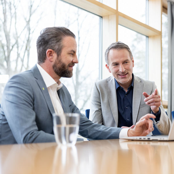 DATEV Mitarbeiter und Verantwortlicher in der Verwaltung im Büro am Tisch mit Laptop sprechen miteinander