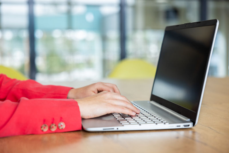 Eine Person tippt an einem Laptop 