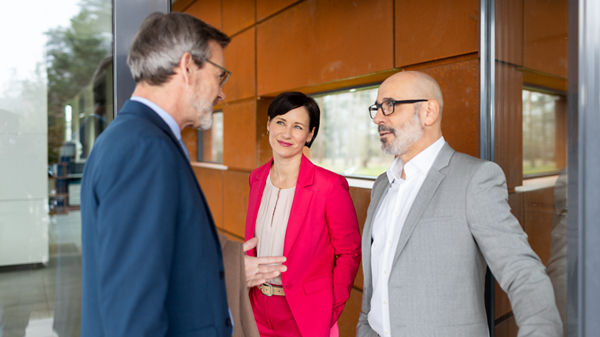 Drei Personen im Büro und unterhalten sich im Flur