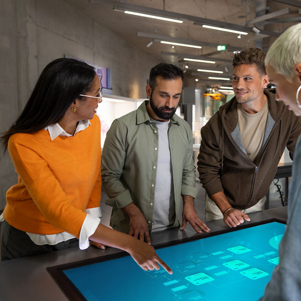 Vier Personen schauen auf ein Whiteboard und besprechen etwas