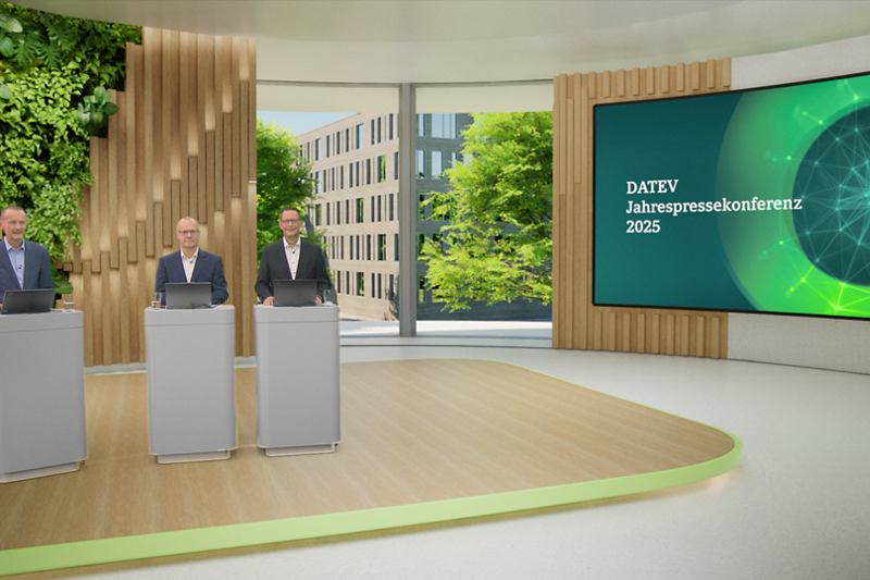 Drei Männer in dunklen Anzügen stehen an einzelnen grauen Stehpulten mit Laptops im modernen DATEV-Studio. Im Hintergrund links eine grüne Pflanzenwand, mittig ein Fenster mit Blick auf ein modernes Bürogebäude und Bäume, rechts ein großer Bildschirm mit der Aufschrift ‚DATEV Jahrespressekonferenz 2025‘ und einer abstrakten grünen Netzgrafik.