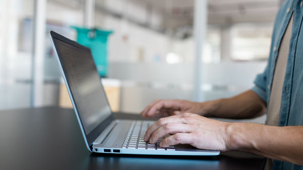 Hände tippen auf einem Laptop.