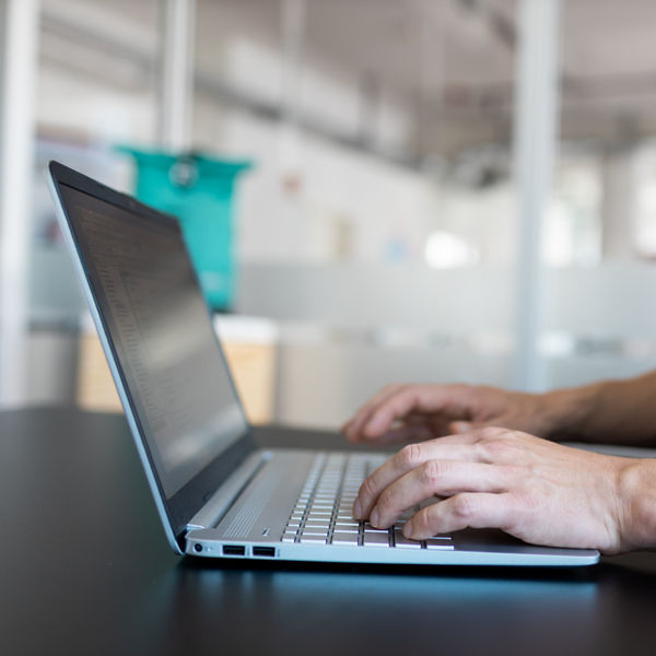 Laptop mit Händen, die auf der Tastatur tippen