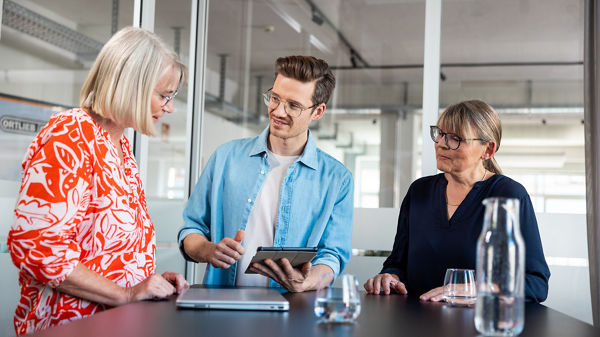 Drei Kollegen besprechen etwas im Büro. 