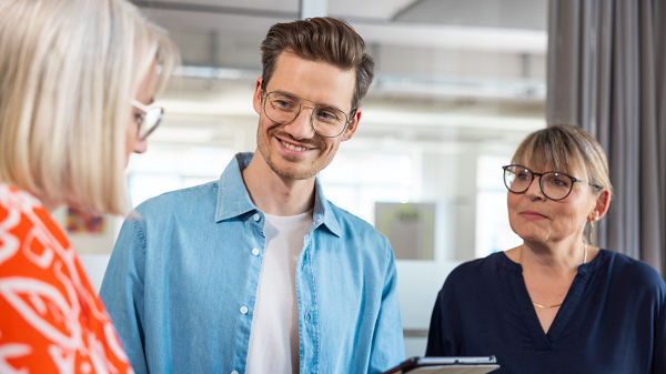 Drei Personen schauen auf ein Tablet.