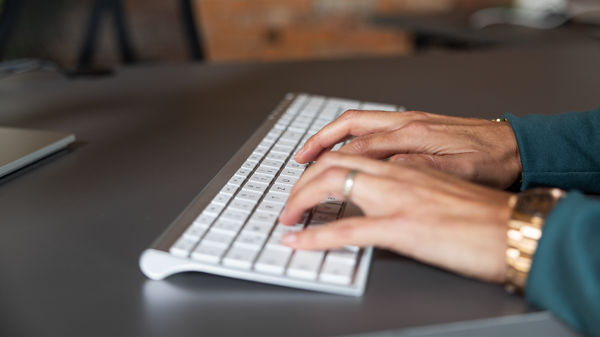 Das Bild zeigt Hände die auf einer Tatstatur etwas eintippen. 