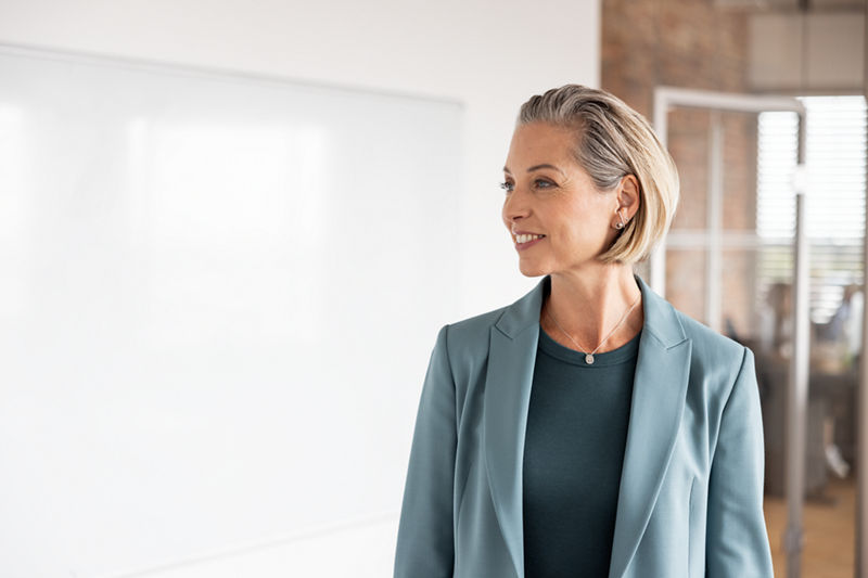 Eine Frau im Blazer lächelt und schaut nach links. 