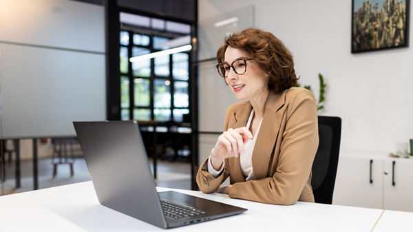 Frau sitzt im Büro vor dem Laptop