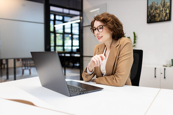 Frau sitzt im Büro vor dem Laptop
