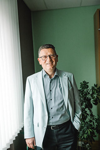 Portrait von Manuel P. Stöhr in grauem Sakko vor grünem Hintergrund.