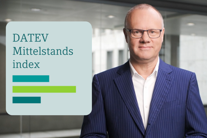 Ein Mann im dunkelblauen Nadelstreifenanzug mit weißem Hemd und Brille steht vor einer modernen Glasfassade. Links im Bild befindet sich eine Grafik mit dem Titel ‚DATEV Mittelstandsindex‘ sowie drei unterschiedlich langen horizontalen Balken in Blau- und Grüntönen.