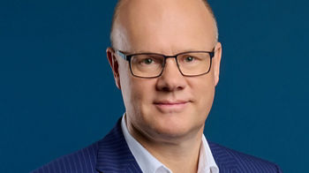 Robert Mayr, CEO der DATEV eG, im Porträt mit blauem Nadelstreifenanzug und weißem Hemd vor blauem Hintergrund.