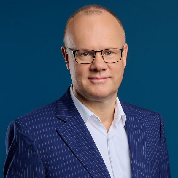 Robert Mayr, CEO der DATEV eG, im Porträt mit blauem Nadelstreifenanzug und weißem Hemd vor blauem Hintergrund.